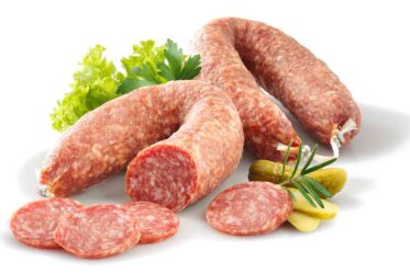 Produktaufnahme einer Mettwurst auf hellem Hintergrund, grobkörnige Fleischstruktur deutlich sichtbar, traditionelle Rohwurst, frische rote Farbgebung, hochwertige Fleischware, Detailfoto für Lebensmittelpräsentation