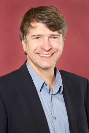 Bruno Jöbkes blickt direkt in die Kamera und zeigt ein freundliches Lächeln.