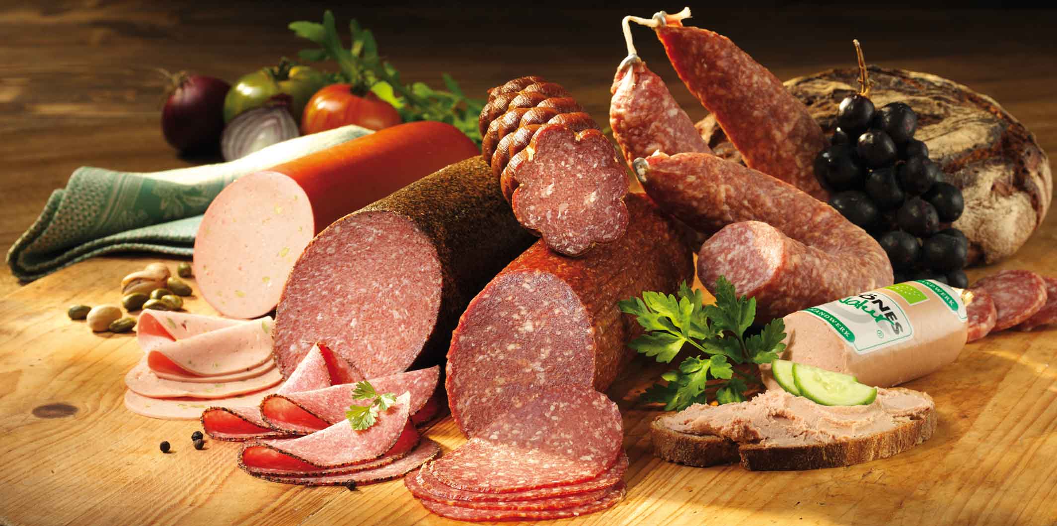 Wurstsortiment auf Holzbrett dekoriert mit frischen Kräutern.