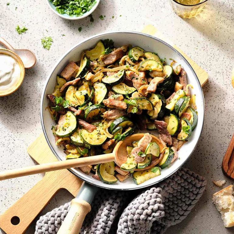 In einer Pfanne serviertes geschnetzeltes Kräuter-Gyros, dekoriert mit aromatischen Kräutern und Gewürzen.